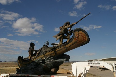  large bronze canoe with a hunter in the front, an indian in the back and an Elk pelt in the middle